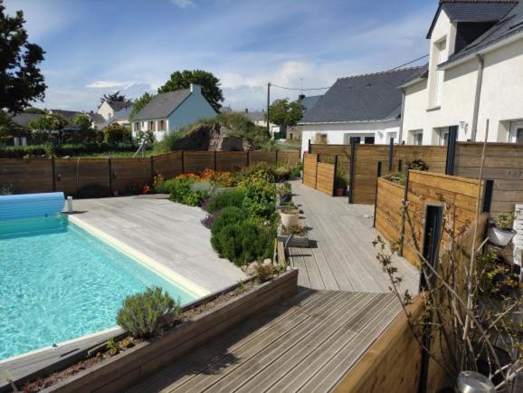 un patio trasero con piscina y terraza de madera en les salines de la turballe, en La Turballe