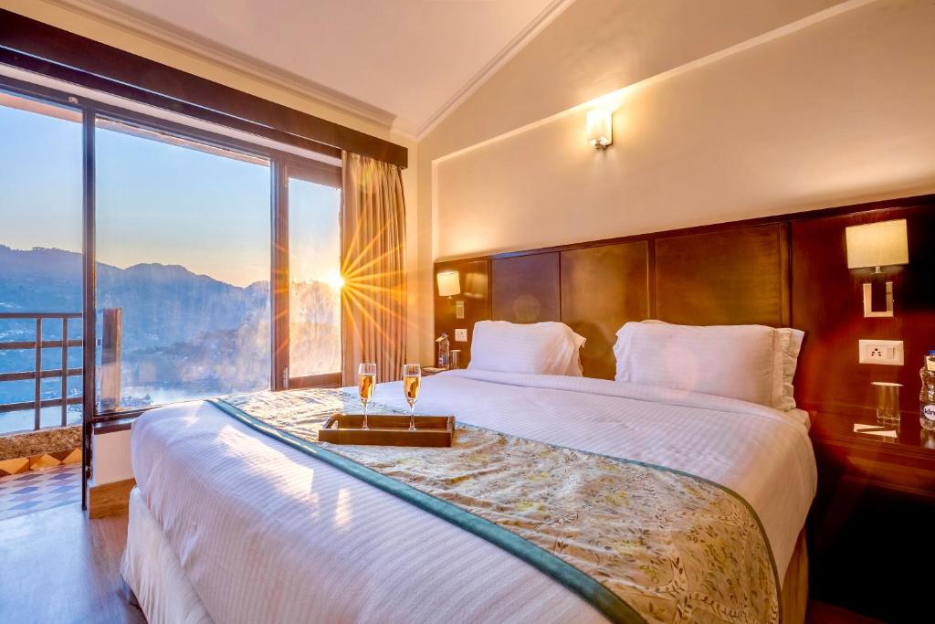a bedroom with a large bed with a large window at Rosewood Retreat Bhimtal in Bhīm Tāl