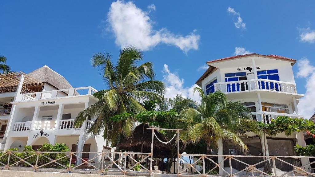 a white building with palm trees in front of it at Villa Mina beachhouse in Jambiani