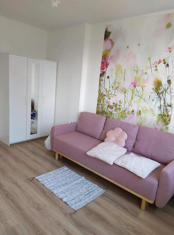 a purple couch in a living room with a flower mural at Apartament przy basenie in Giżycko