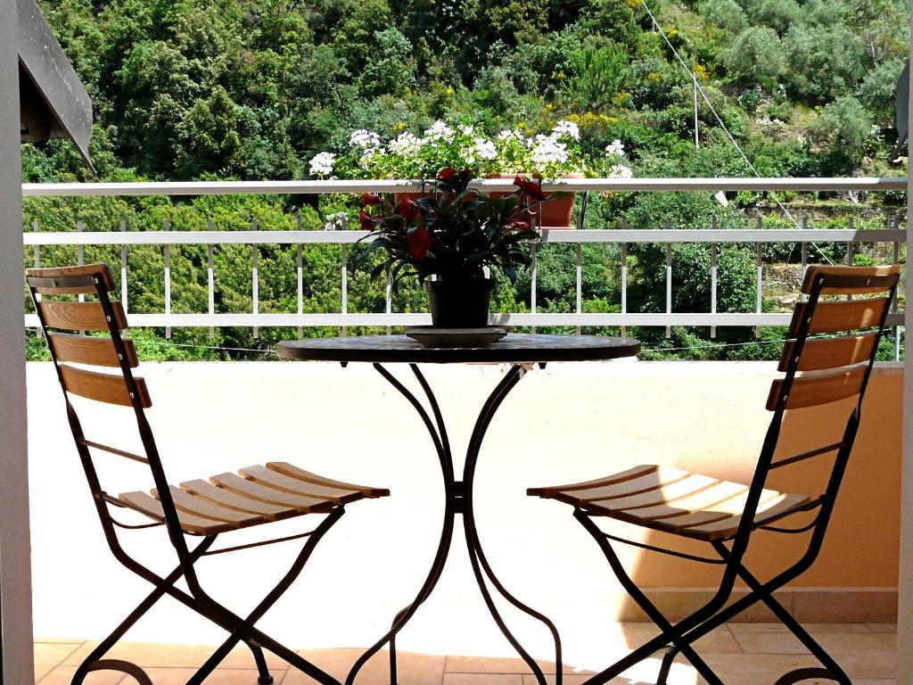 2 sillas y una mesa con un jarrón de flores en el balcón en L'Albicocco, en Dolceacqua