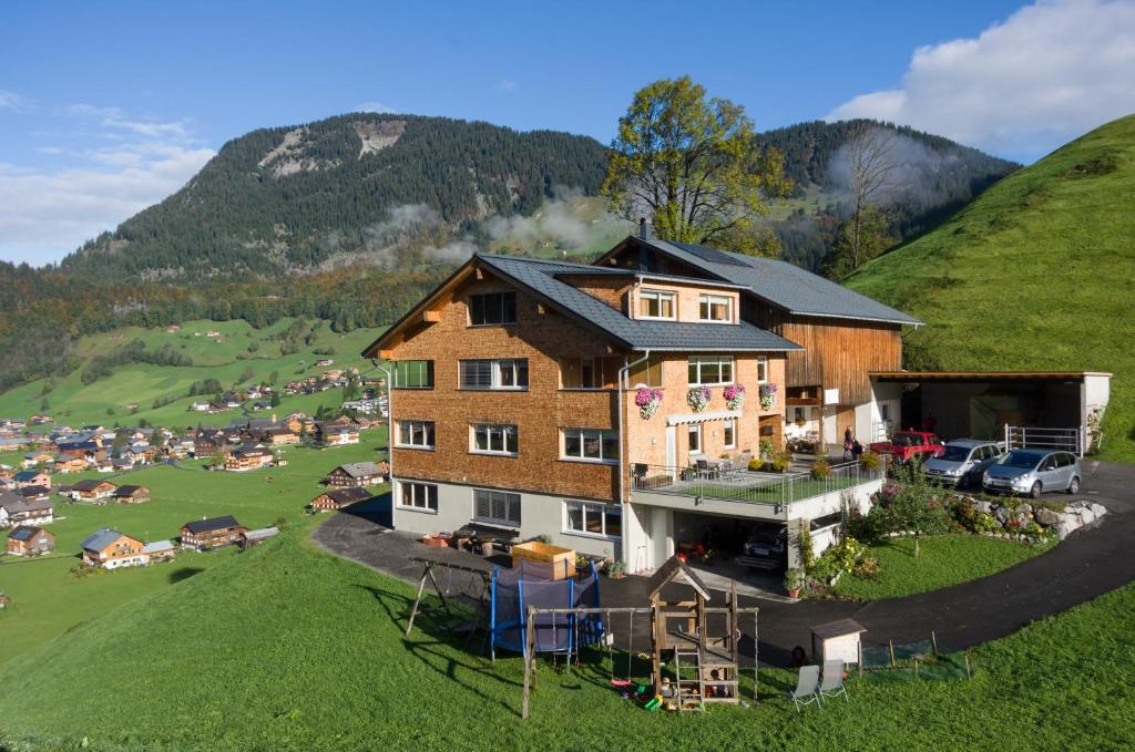 uma casa grande numa colina num campo em Panoramahof Eggele em Schoppernau