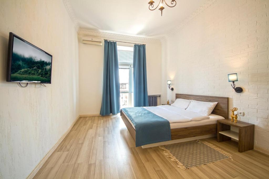a bedroom with a bed and a tv on a wall at Scandinavian Apartments in Kyiv