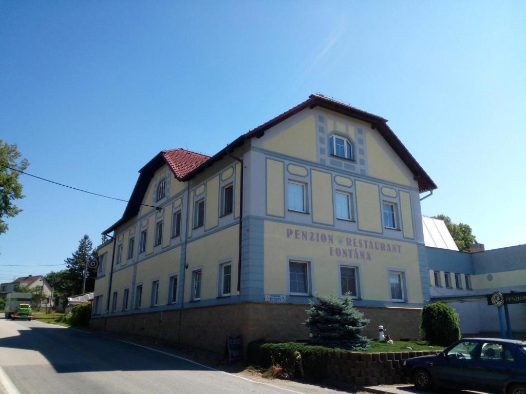 un gran edificio blanco al lado de una calle en Penzion Fontána, en Sudoměřice