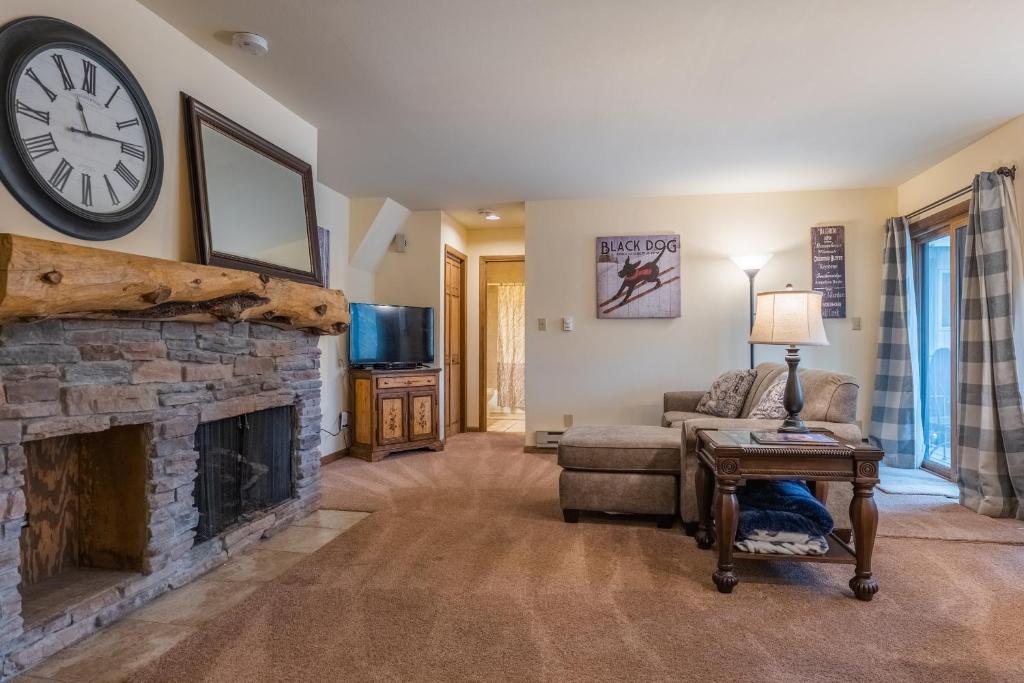 a living room with a fireplace and a clock on the wall at 1100 Flying Dutchman condo in Keystone