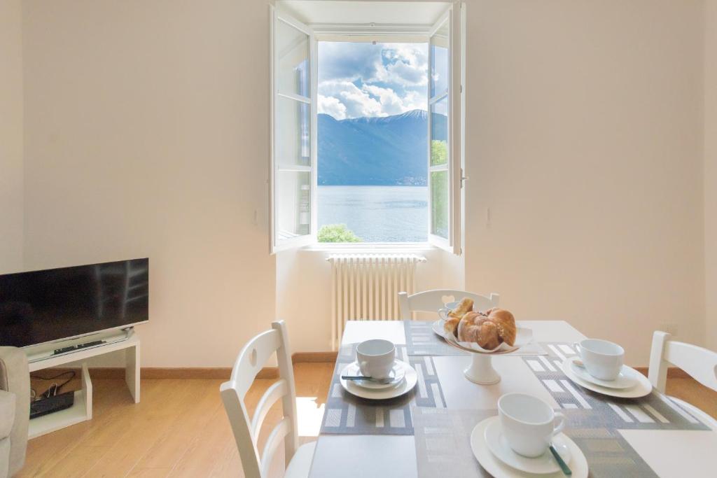 comedor con mesa y ventana en Tina's Window on Lake Como by Rent All Como, en Mezzegra