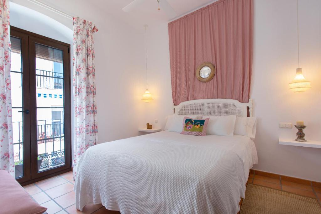 - une chambre avec un lit blanc et une horloge murale dans l'établissement La Morada Mas Hermosa, à Marbella