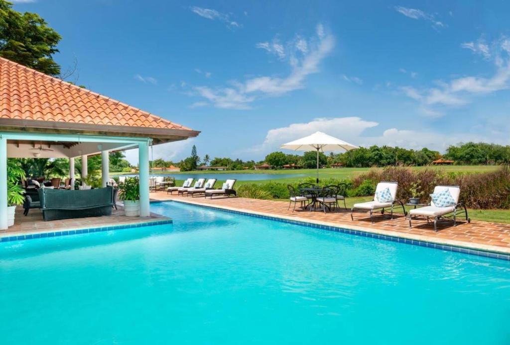 a swimming pool with chairs and umbrellas at Los Lagos 19- Golf and Lake View 5-Bedroom Villa in La Romana