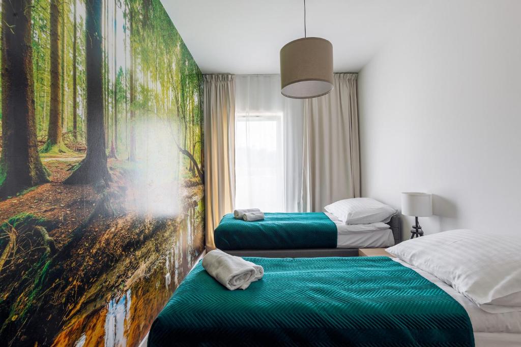 Twin bedroom with forest wall mural, teal bedspreads, bedside lamp, soft natural light.