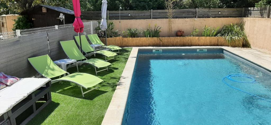 a swimming pool with lawn chairs and an umbrella at le Mas d'Hubert in LʼIsle-sur-la-Sorgue
