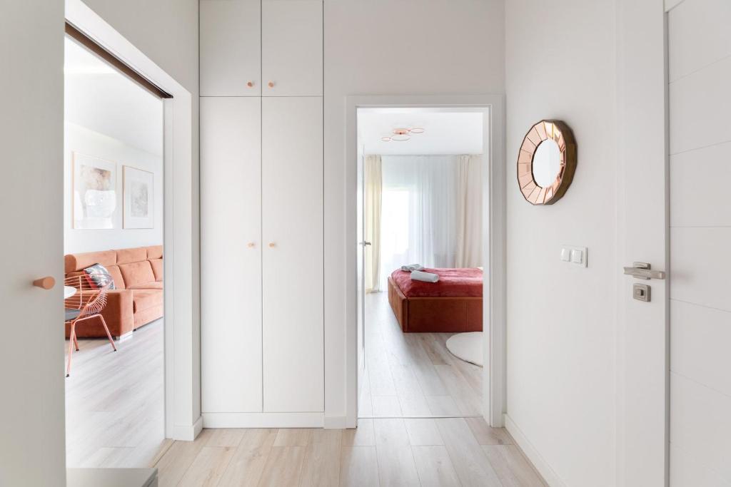 Bright hallway with tall white cabinets, doorway views into living area and bedroom beyond.