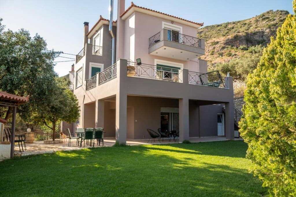 a large white house with a green yard at Akrivi's House in Kalamata in Kalamata