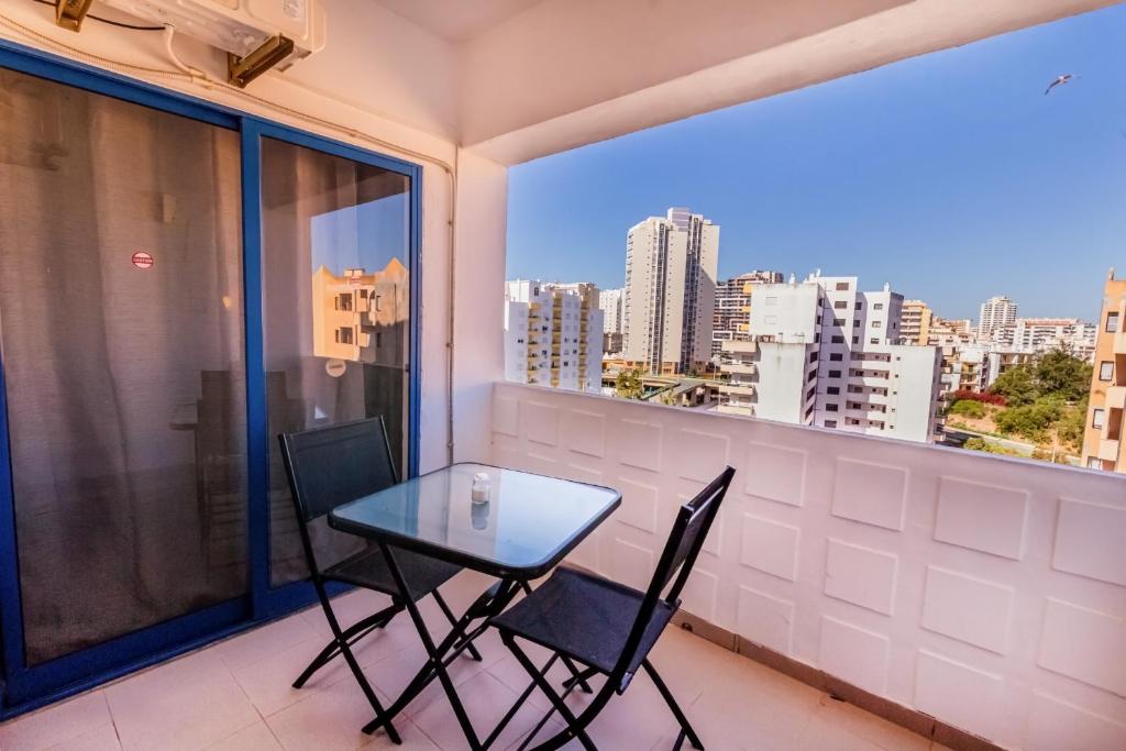 a table and chairs on a balcony with a view of the city at Apartment in Praia da Rocha with A-C, Terrace in Portimao in Portimão