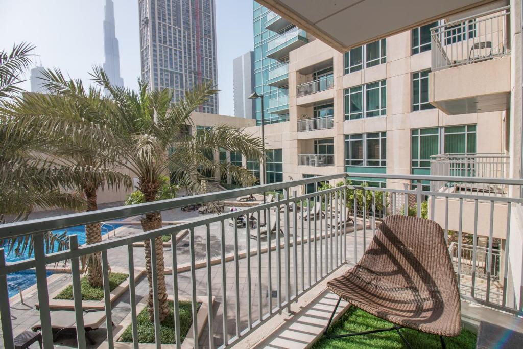 a chair on a balcony with palm trees and buildings at Luxury studio at Downtown! Full Burj Khalifa View! Burj Views L in Dubai