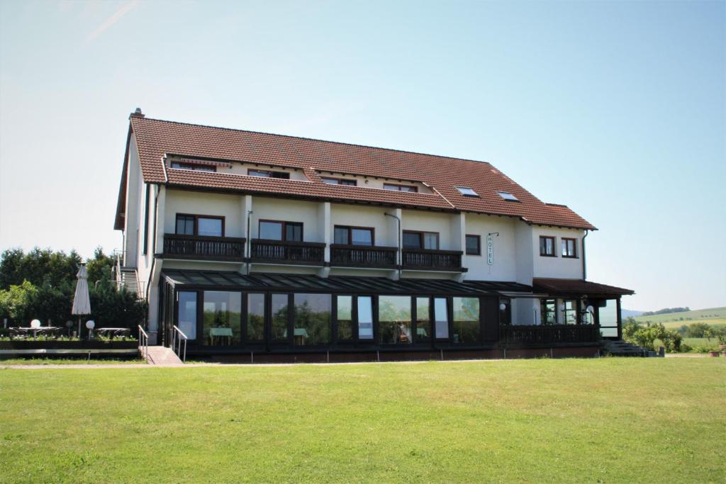 een groot huis met een groot gazon ervoor bij Hotel Waldschlösschen in Dankmarshausen