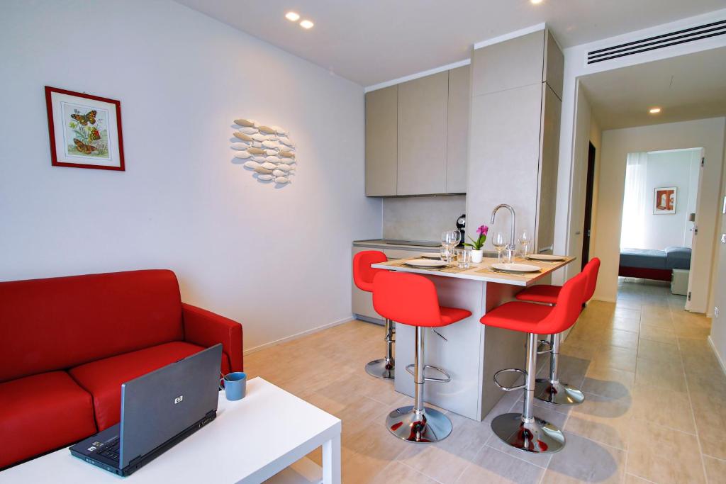 een woonkamer met een rode bank en een keuken bij Casa Plauto in Bellaria-Igea Marina