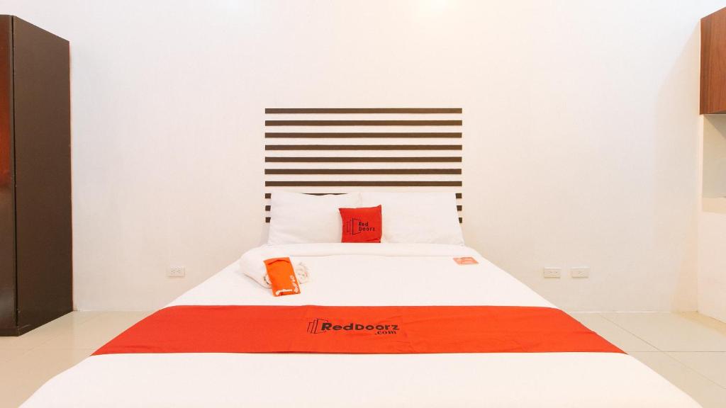 um quarto com uma cama com um cobertor vermelho e laranja em RedDoorz @ Jardin LRT Tayuman Manila em Manila