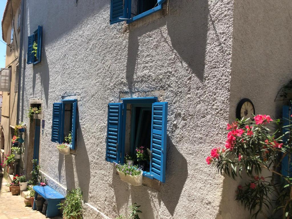 a building with blue shutters and flowers on it at Blue Bench Krk in Krk