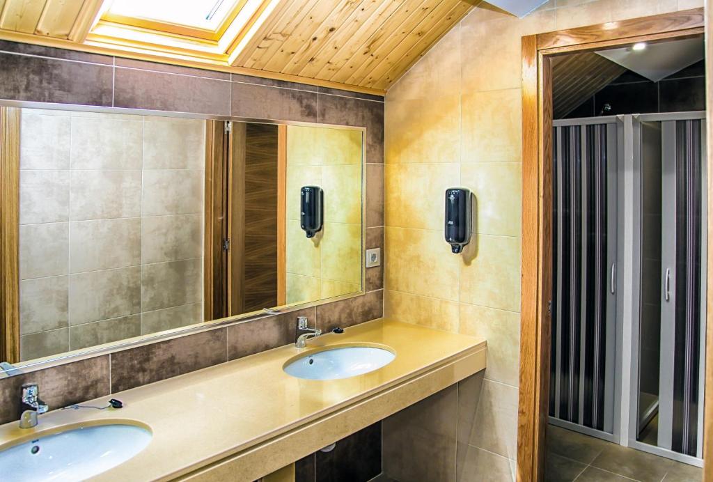 uma casa de banho com 2 lavatórios e um espelho em Albergue San Anton em Melide