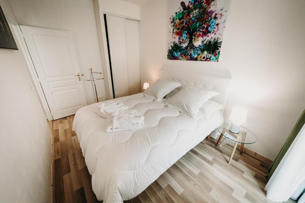 ein weißes Bett in einem Zimmer mit einem Gemälde an der Wand in der Unterkunft Charmant appartement 4 étoiles Bella Vita Zen in Aix-les-Bains