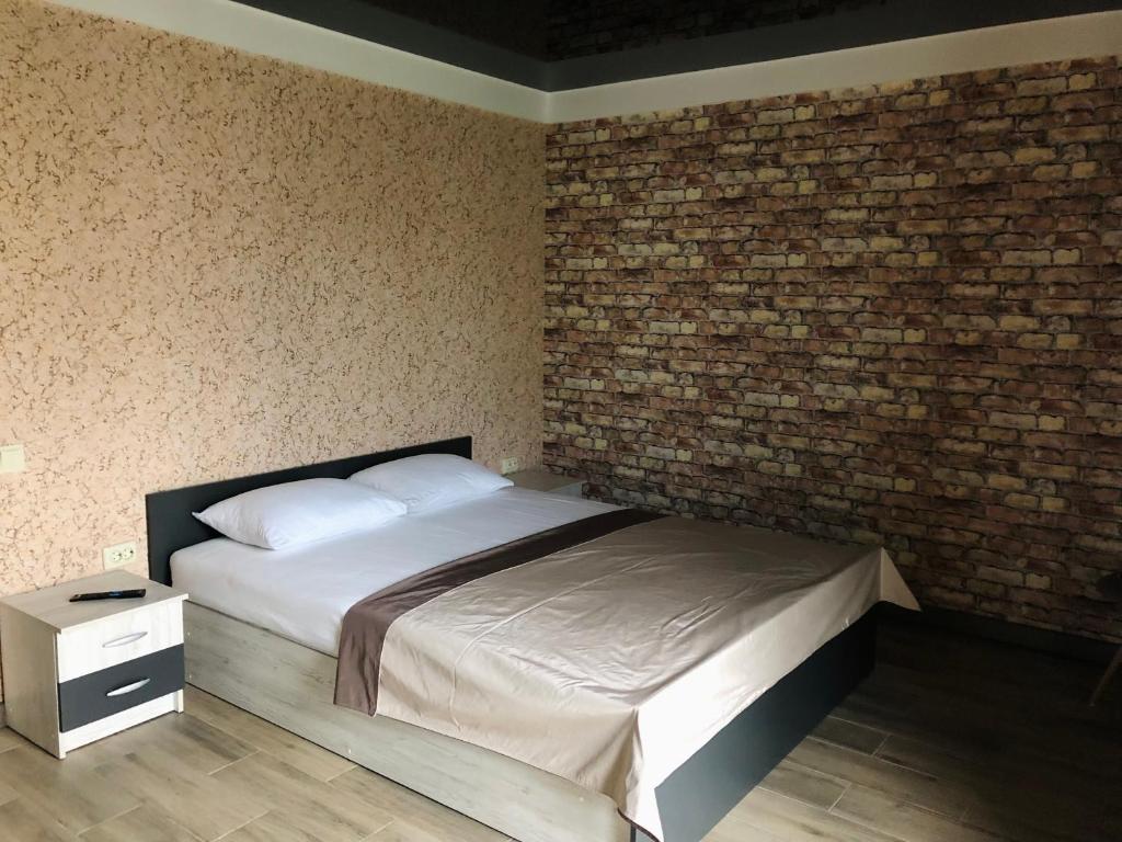 a bedroom with a bed and a brick wall at Bloom Hotel in Kharkiv