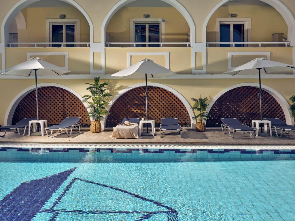 a hotel with a swimming pool with chairs and umbrellas at Alkyonis hotel in Laganas