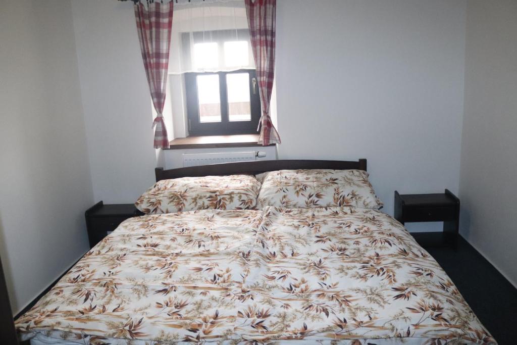 a bed with a comforter and a window at apartmány Kynast in Albrechtice v Jizerských horách
