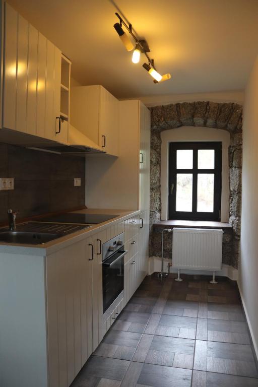 a kitchen with white cabinets and a window at apartmány Kynast in Albrechtice v Jizerských horách