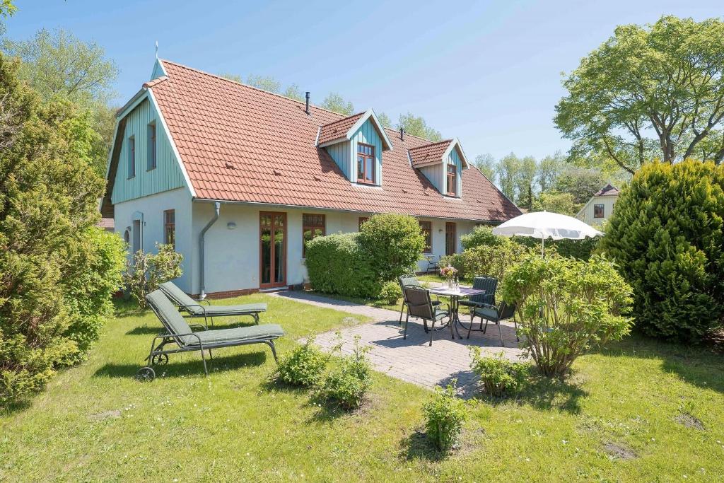 een huis met een tafel en stoelen in de tuin bij Ferienhaussiedlung Strandperlen Buchenhof 4a (Typ IV) in Wustrow