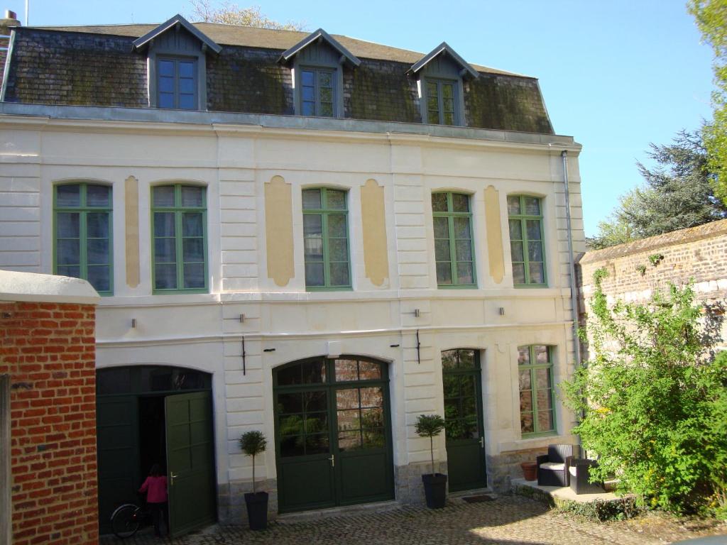 アラスにあるLa Cour des Carmesの緑のドアと窓が特徴の白い大きな建物