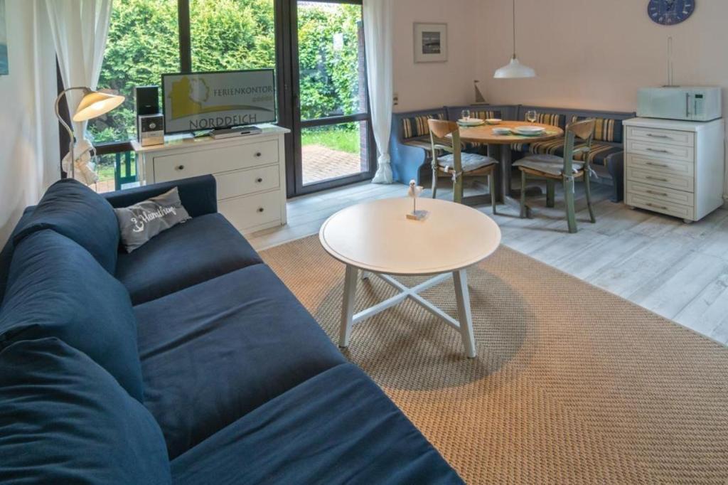 een woonkamer met een blauwe bank en een tafel bij Fewo-Mientje-2-Haustiere-erlaubt-WLAN-kostenlos in Norddeich