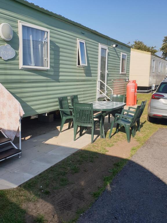 einem Picknicktisch und Stühlen vor einem grünen Wohnwagen in der Unterkunft Inviting 3-Bed Caravan in Porthcawl in Porthcawl