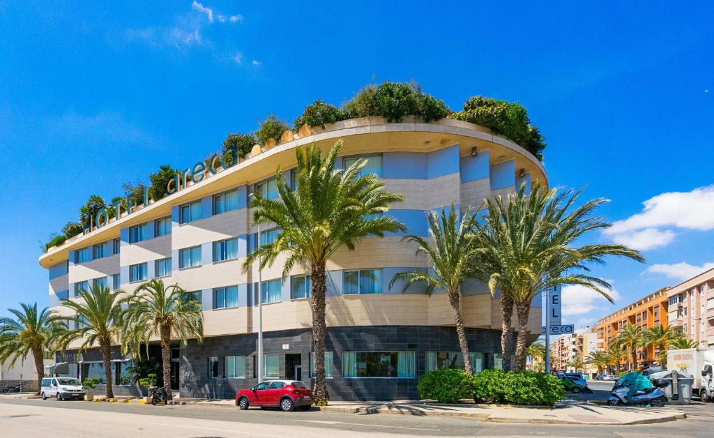a building with palm trees in front of it at Hotel Areca in Torrellano