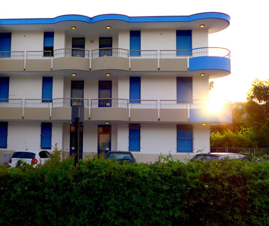 un edificio blanco con ventanas azules en un aparcamiento en Residence Il Sole, en Porto Corsini