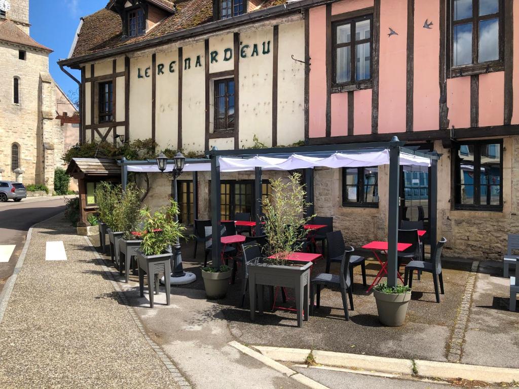 un restaurant avec des tables et des chaises en face d'un bâtiment dans l'établissement Auberge du Renard'eau, à Bèze