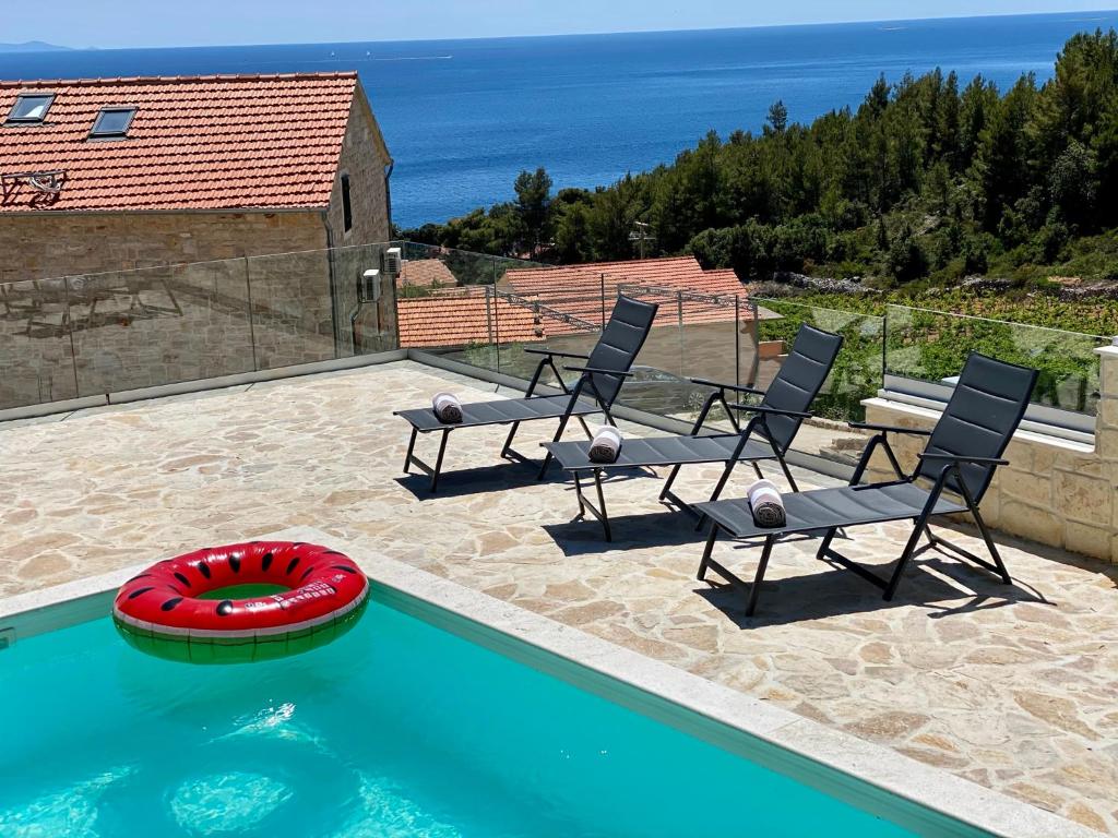 a swimming pool with two chairs and a red frisbee at Kuća za odmor "Villa Oliva" in Ivan Dolac