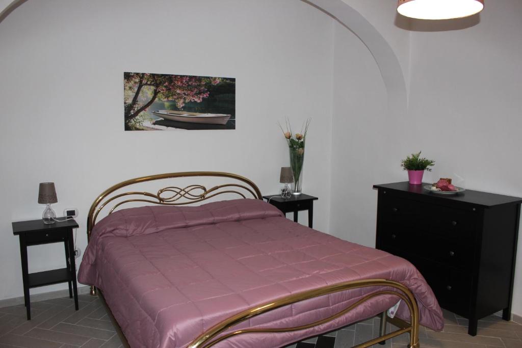 1 dormitorio con 1 cama con manta morada y 2 mesas en Casa Vacanze Nonna Raffa, en Amalfi