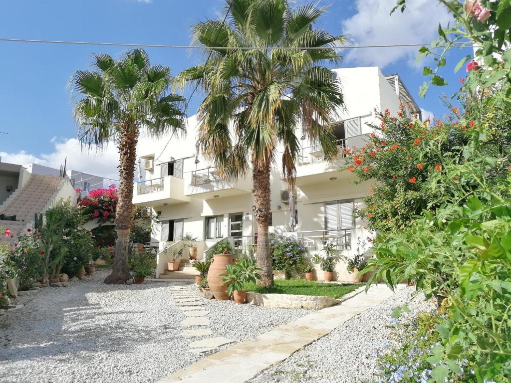 a white house with palm trees in front of it at Lion-Suites in Kalyves