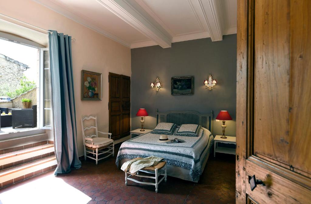 una camera con un letto e due sedie e una finestra di Les chambres du Vieux Bistrot a Cabrières-dʼAvignon