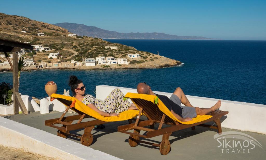 un homme et une femme assis sur des chaises longues sur la plage dans l'établissement Alopronoia Sea Breeze, à Sikinos