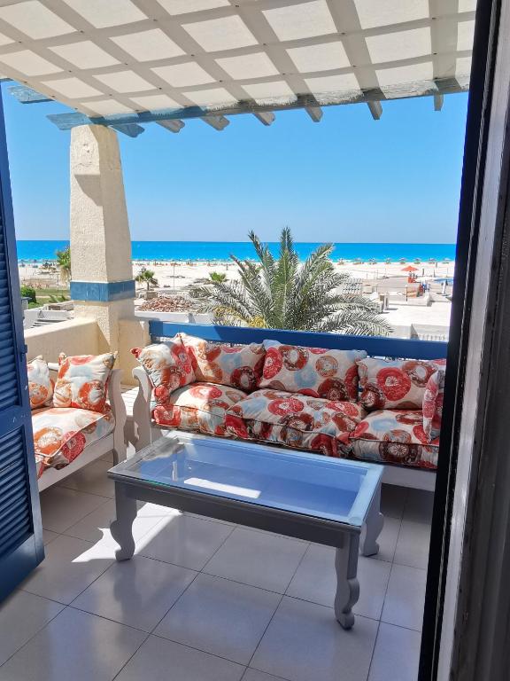 a couch on a balcony with a view of the beach at La Stanza Chalet in Dawwār ‘Abd al ‘Aţī Abū ‘Ajūz