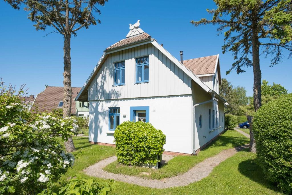 une maison blanche avec un toit en gambrel dans l'établissement Ferienhaussiedlung Strandperlen Weidenhof 5b (Typ VII), à Wustrow