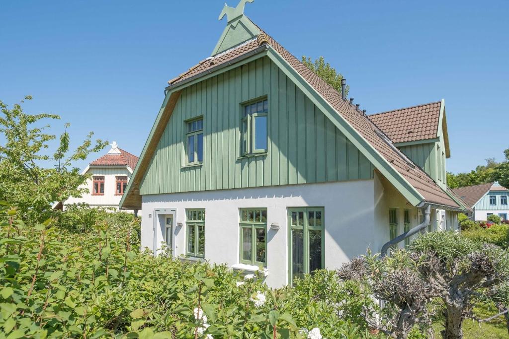 a green and white house with a green roof at Ferienhaussiedlung Strandperlen Weidenhof 3c (Typ II) in Wustrow