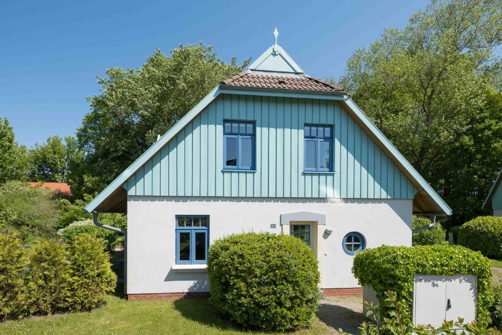 Casa blanca y verde con techo en Ferienhaussiedlung Strandperlen Weidenhof 8d (Typ IV), en Wustrow