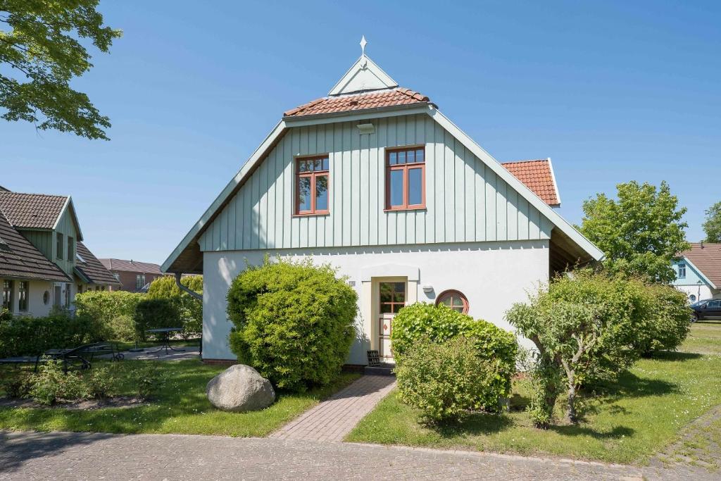 una casa verde e bianca con cespugli e alberi di Ferienhaussiedlung Strandperlen Buchenhof 4d (Typ IV) a Wustrow