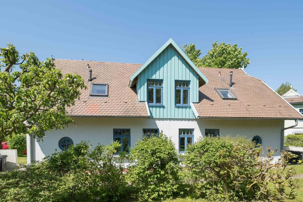 a white house with a blue roof at Ferienhaussiedlung Strandperlen Weidenhof 6a (Typ VII) in Wustrow