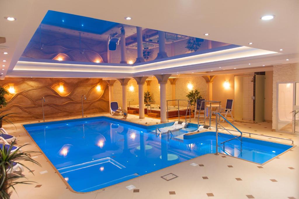 une grande piscine intérieure d'eau bleue dans un bâtiment dans l'établissement Hotel Adam & Spa, à Kudowa-Zdrój