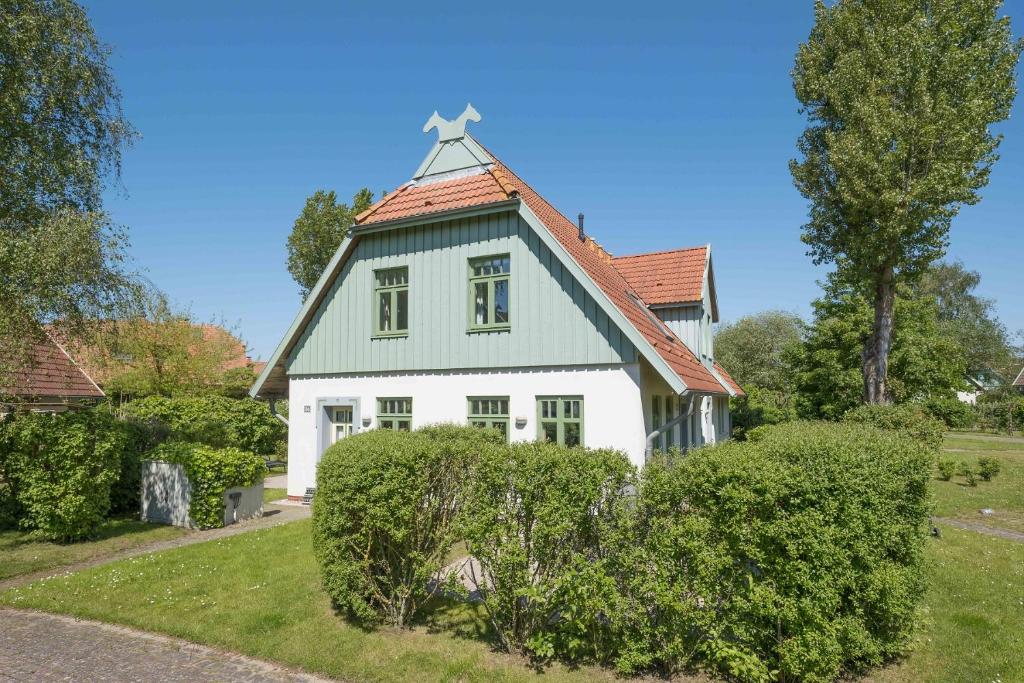 a white house with a cross on the roof at Ferienhaussiedlung Strandperlen Sanddornhof 3c (Typ II) in Wustrow