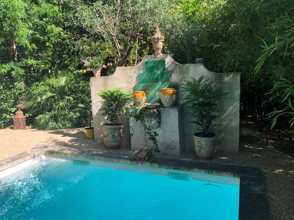 a swimming pool with potted plants and a fountain at Maison d'Hôtes La Boca in Sommières