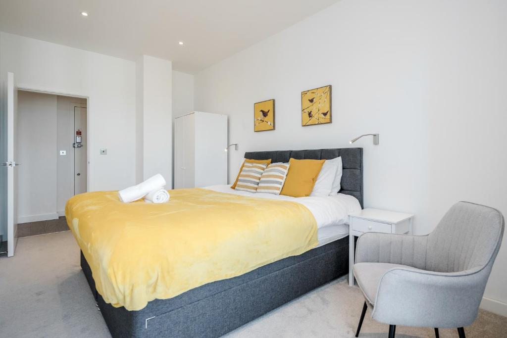 a bedroom with a large bed and a chair at Top Floor Luxury 2 Bedroom St Albans Apartment - Free WiFi in St. Albans